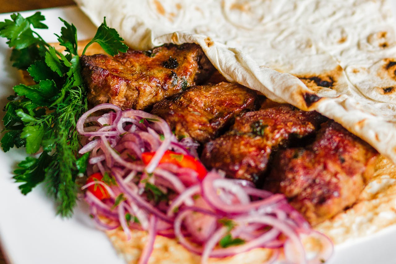 Close-up of a grilled kebab with onions and herbs, perfect for a tasty meal.