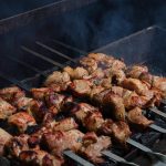 Juicy chicken skewers grilling over hot coals with smoke rising, perfect summer barbecue.