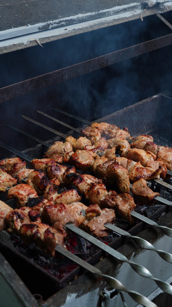 Juicy chicken skewers grilling over hot coals with smoke rising, perfect summer barbecue.
