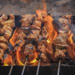 Juicy skewers of grilled meat sizzling over open flames, creating a tasty barbecue feel.