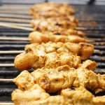 Close-up of juicy chicken skewers grilling over charcoal, showcasing a delicious barbecue meal.