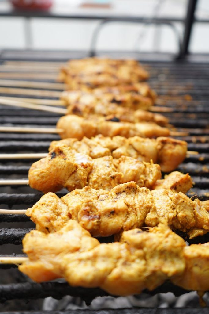 Close-up of juicy chicken skewers grilling over charcoal, showcasing a delicious barbecue meal.